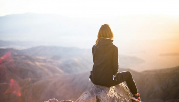 A girl setting on the top of a mountain 