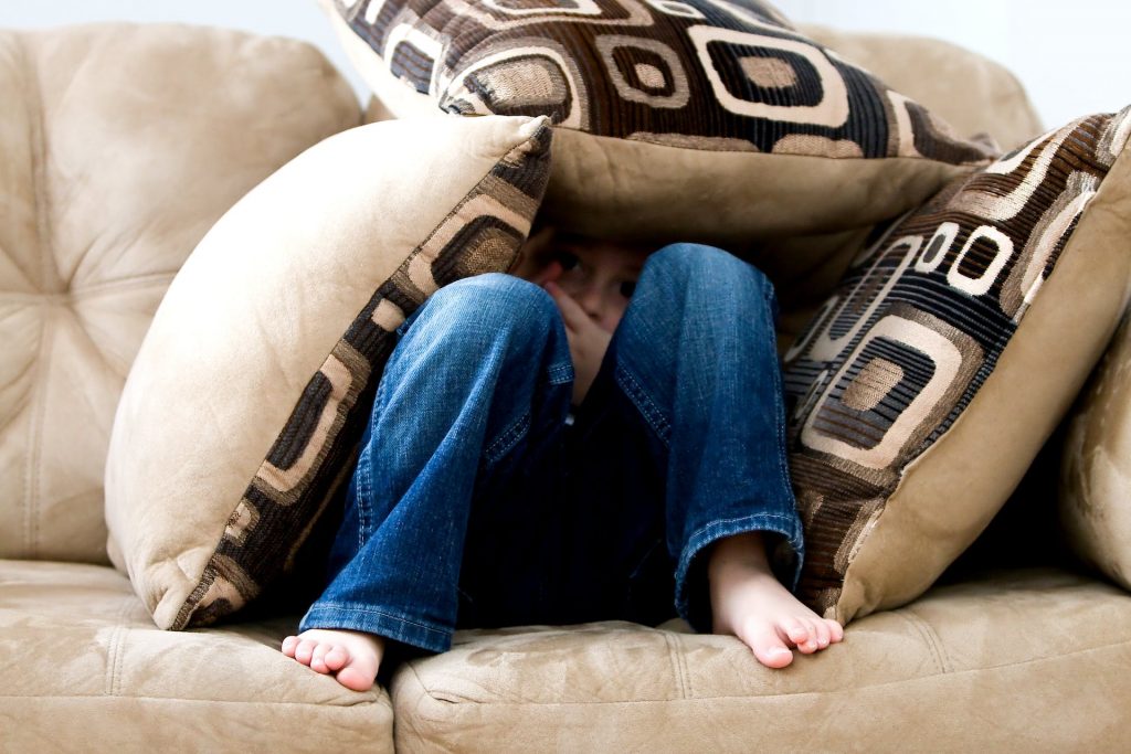 child under cushions