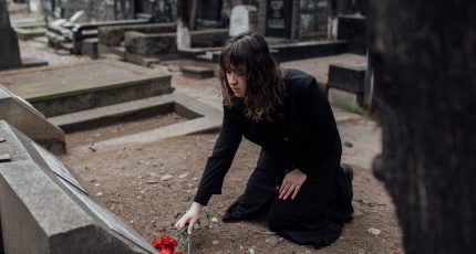 A girl gives a flower to a grave