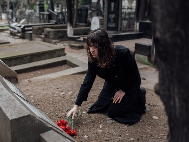 A girl gives a flower to a grave